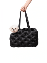 hand-holding-black-kamamuta-airy-pet-bag-with-white-small-dog-sitting-inside-peeking-out-from-side-slanted-opening