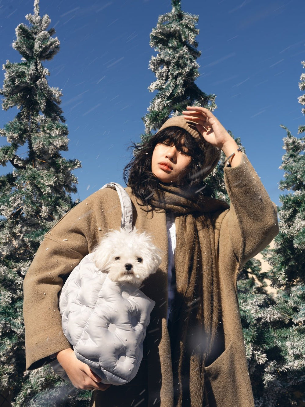 person-carrying-white-kamamuta-airy-pet-bag-on-right-shoulder-with-maltese-dog-head-out-winter-trees-background