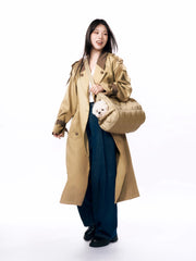 woman-in-trench-coat-wearing-kamamuta-pinecone-pet-carrier-crossbody-with-white-maltese-dog-peeking-out