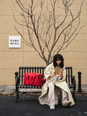 woman-sitting-on-bench-reading-magazine-with-red-kamamuta-pet-shadow-stealth=whisper-square-bag-placed-on-right-side