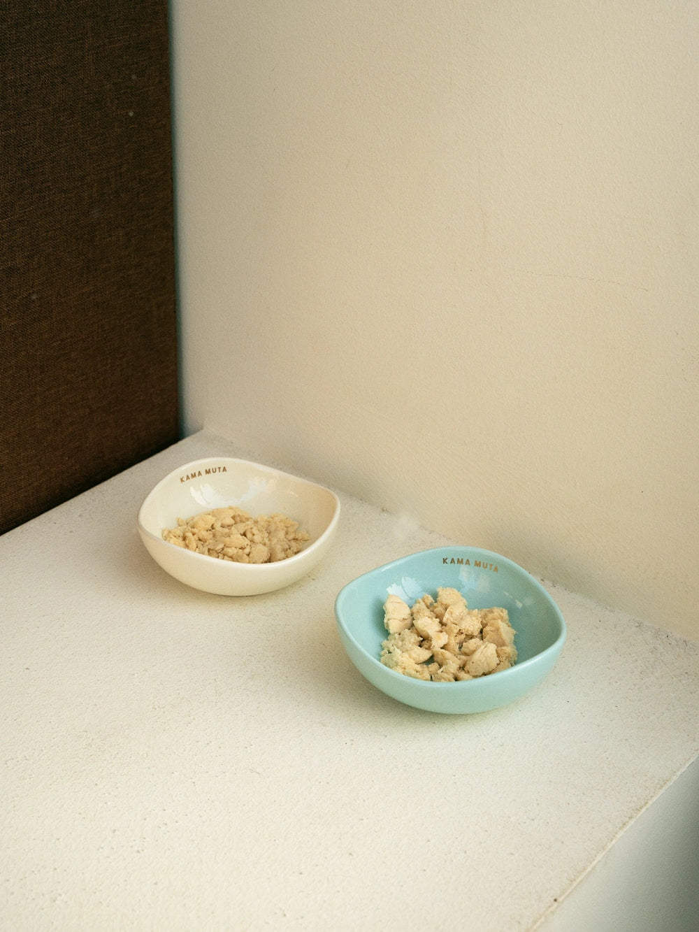 green-and-yellow-kamamuta-pet-pod-bowl-filled-with-food-placed-against-white-wall