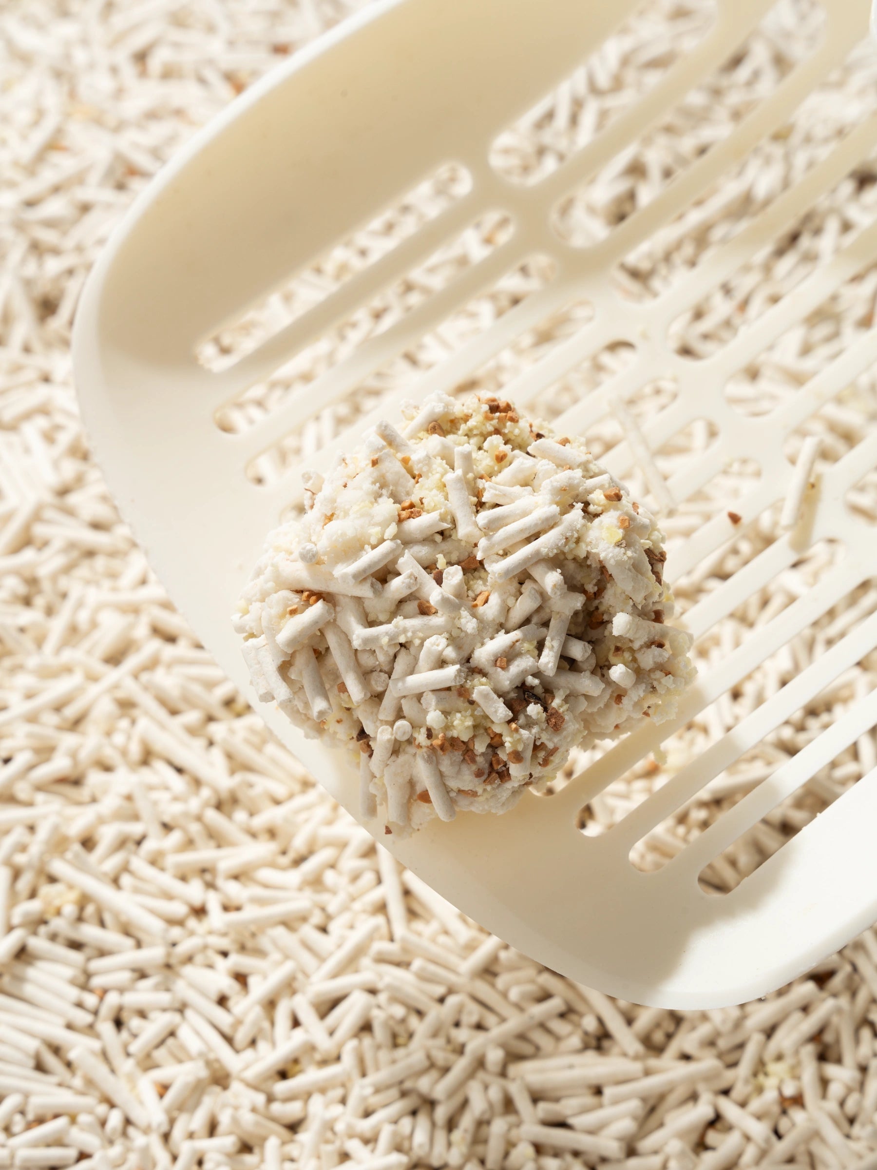close-up-of-kamamuta-tofu-cat-litter-clumping-held-by-scoop-with-litter-background